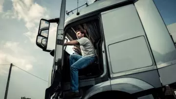 Man zit achter het stuur in een stilstaande vrachtwagen met de deur open